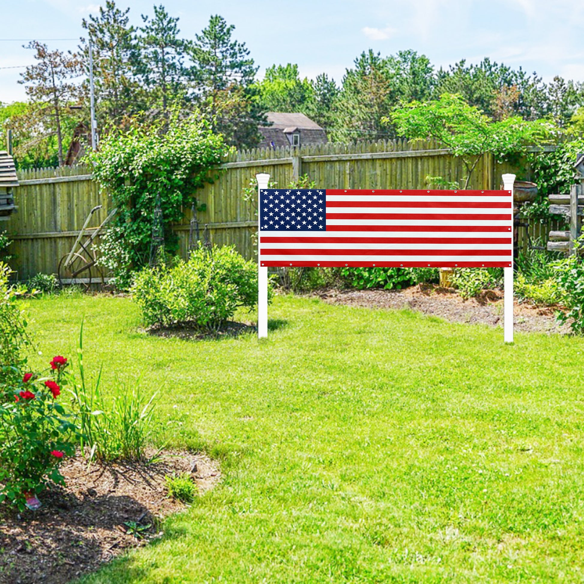 American flag on a white stand in a garden with green grass and trees