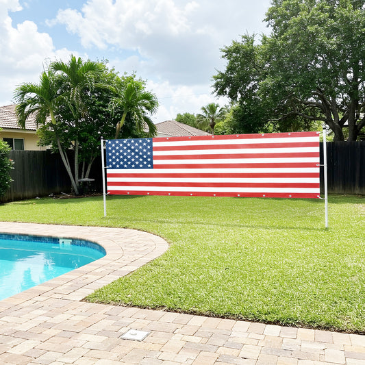 A vibrant American flag stands tall in a backyard, symbolizing patriotism against a clear sky.  